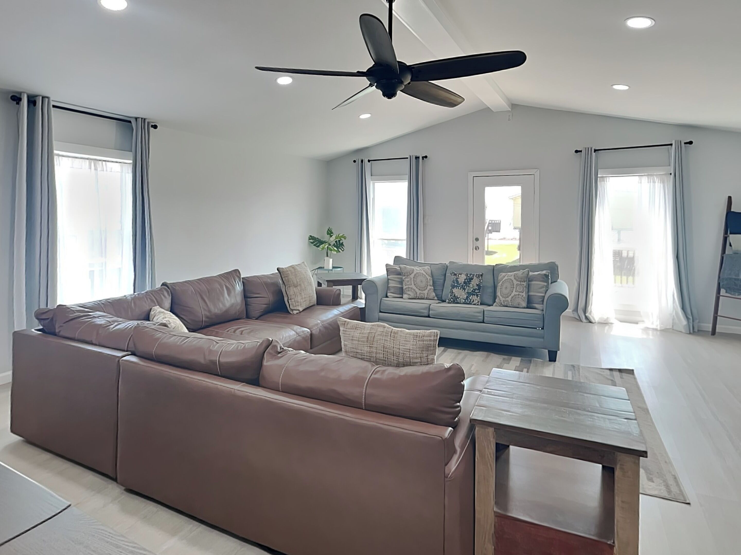 A modern living room with a brown leather sofa, a blue sofa, and a wooden coffee table.