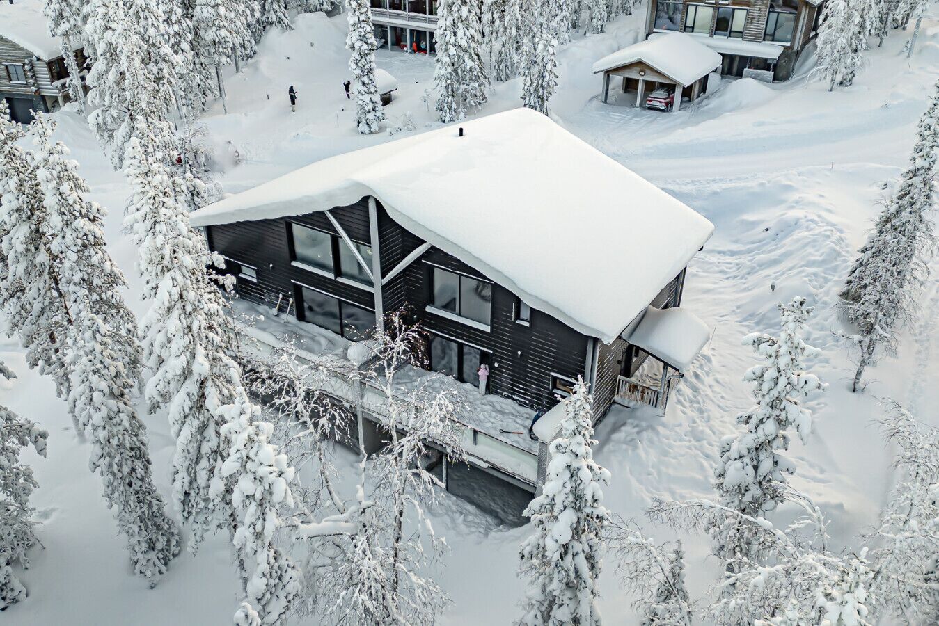Un chalet moderne à deux étages, entouré d’arbres couverts de neige.