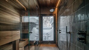 A modern bathroom with wooden paneling, a glass shower enclosure, and a view of a snowy landscape.