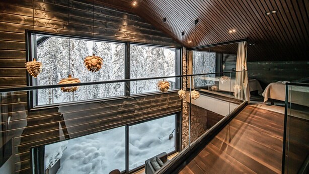 A modern interior with large windows, wooden ceiling, and hanging pendant lights.