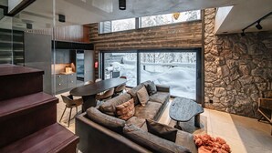 A modern interior with a dining area, sofa, and stone wall.