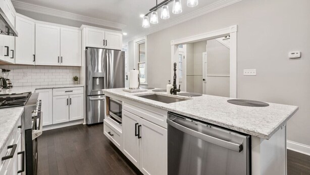 Eine moderne Küche mit weißen Schränken, Edelstahlgeräten, einer Spüle und einem integrierten Geschirrspüler.