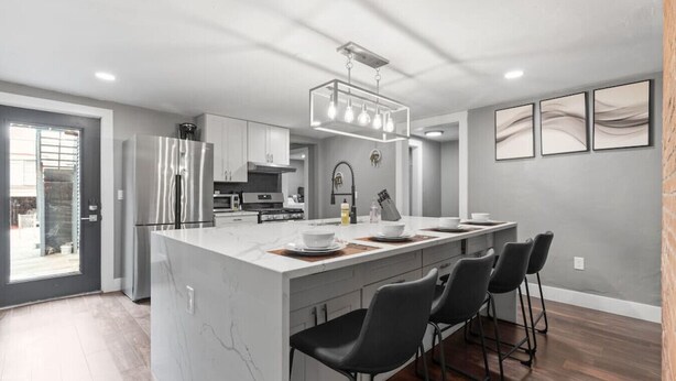 Una cocina moderna con una isla grande, electrodomésticos de acero inoxidable y una lámpara colgante.