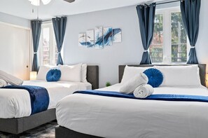 Quarto de hotel com duas camas, uma janela grande e uma obra de arte pendurada na parede.