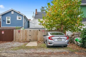 A residential area with a blue house, a wooden fence, and a parked silver car.