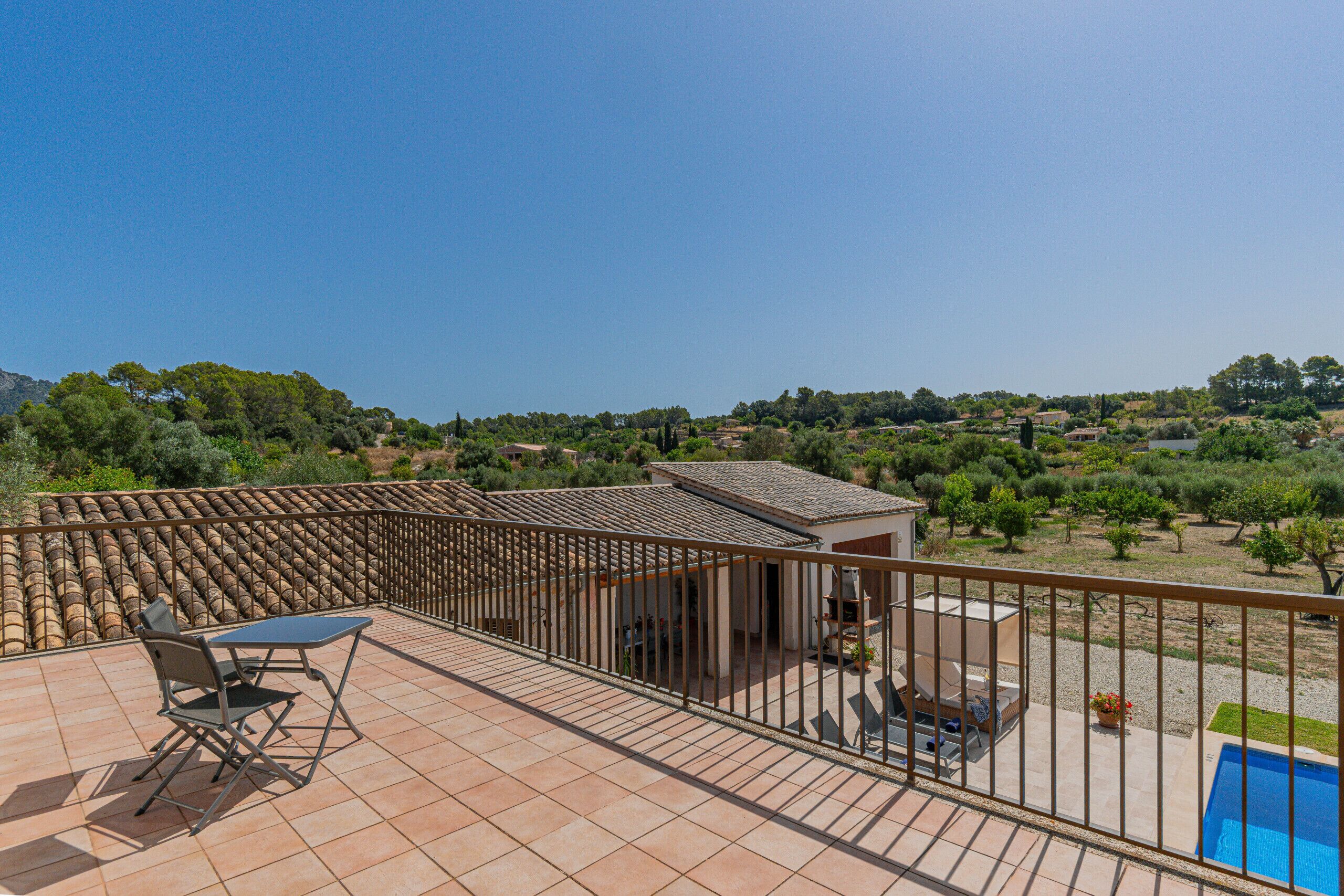 Une terrasse avec une table et des chaises, une piscine et une vue sur le paysage environnant.