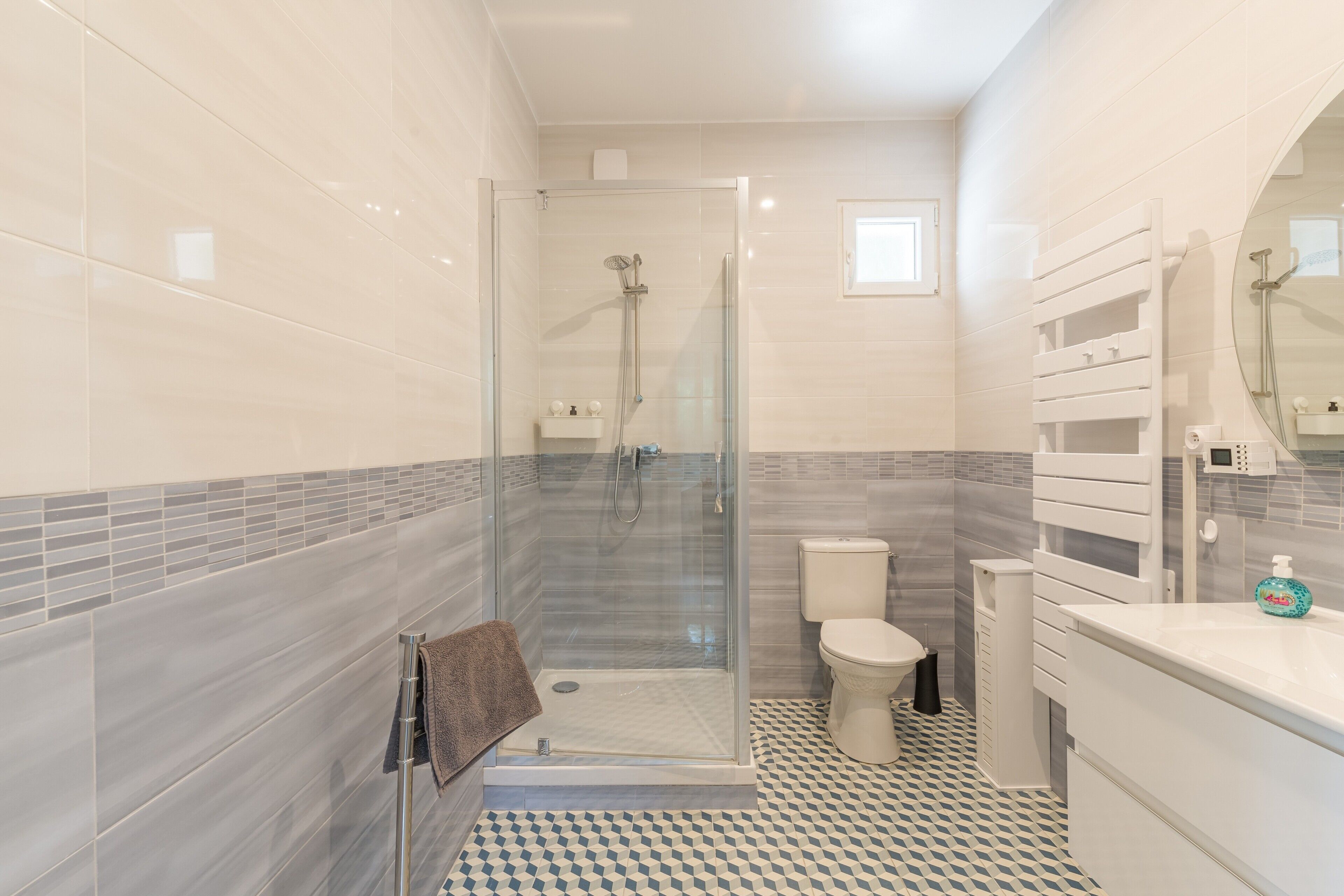 Un baño moderno con ducha acristalada, inodoro y lavamanos con espejo.