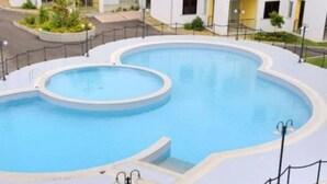 A large, circular swimming pool with a surrounding walkway and a fence. - 1BR Alloggio Apartment (Isca sullo Ionio)