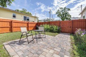 A backyard with a brick patio, two chairs, and a table. - Barefoot Bungalow For 4 (Tampa)