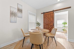 A dining area with a round table, four chairs, and a sliding barn door. - Barefoot Bungalow For 4 (Tampa)