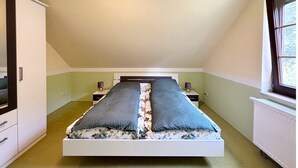 Ein Schlafzimmer mit Bett, Nachttischen, einem Fenster und einer Heizung.