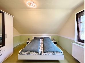 A bedroom with a bed, bedside tables, a window, and a radiator.