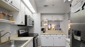 A modern kitchen with white cabinets, stainless steel appliances, and a central island. - Delightful 2-bedroom condo with AC in Fort Myers (Fort Myers)