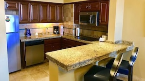A kitchen with granite countertops, stainless steel appliances, and wooden cabinets.