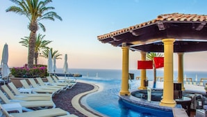 A poolside area with lounge chairs, a pergola, and palm trees.