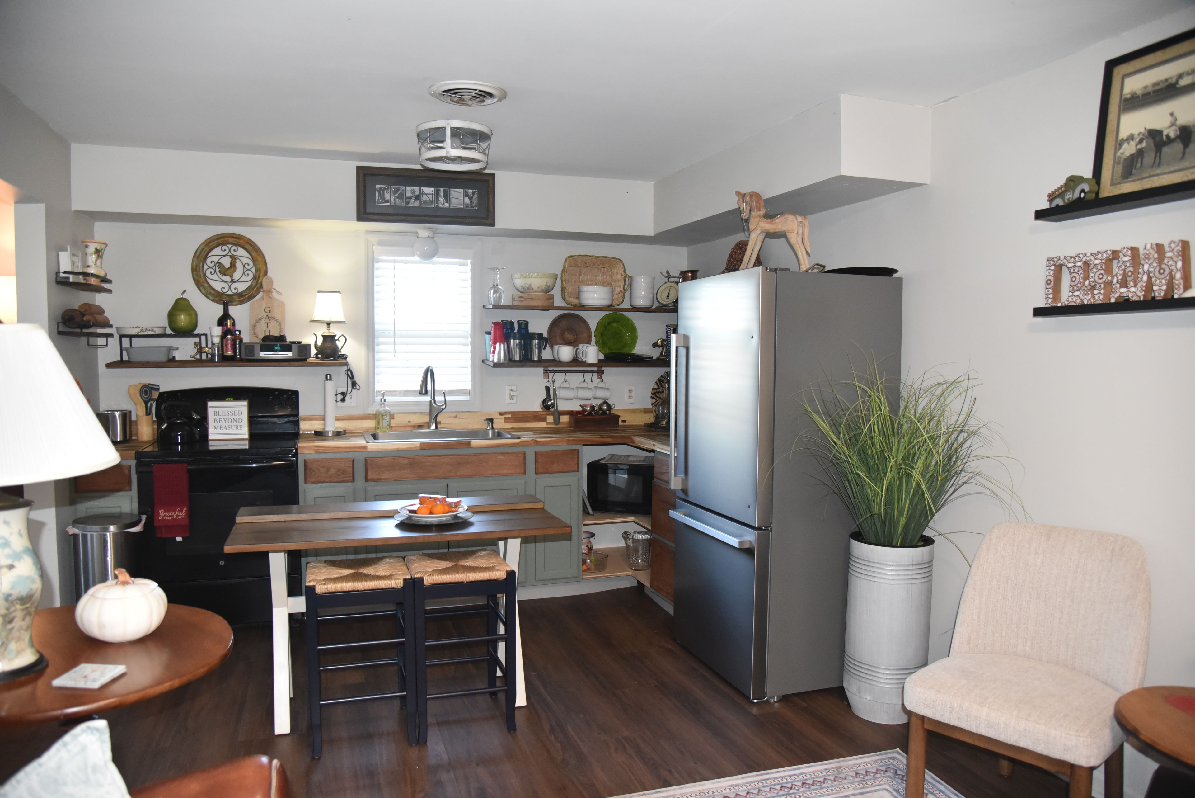 Une cuisine équipée d’un réfrigérateur, d’un évier et de plans de travail en bois. On y trouve une table à manger avec des chaises et une plante en pot.