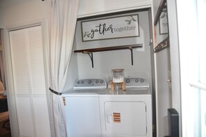 Una kitchenette compacta con estufa, un estante pequeño y un letrero que dice 'gether together'.