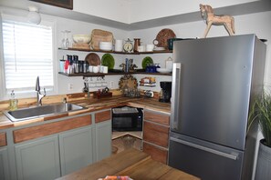 Una cocina con refrigerador de acero inoxidable, encimeras de madera y horno empotrado.