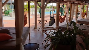 A room with a bed, a small table, and a hammock. - Studio with sea view, beach, air conditioning, bar-restaurant, swimming pool, car rental (Sainte-Anne)