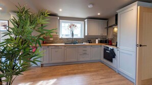 A modern kitchen with light-colored cabinets, a wooden countertop, and a built-in oven. - 4 Bed Holiday Home by Guestz (Rhosneigr)