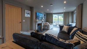 A modern living room with a sofa set, a fireplace, and a television. - 4 Bed Holiday Home by Guestz (Rhosneigr)