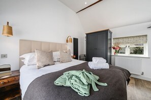 Une chambre moderne avec un grand lit, une armoire sombre, une fenêtre donnant sur un beau paysage et une lampe de chevet.