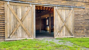 A rustic barn with wooden doors and a gravel path leading to it. - Lakeside Gem: Hot Tub & Game Room in Hancock (Hancock)