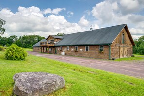 Un grand bâtiment en bois, de style grange, doté d’un porche couvert et d’un gros rocher en premier plan.