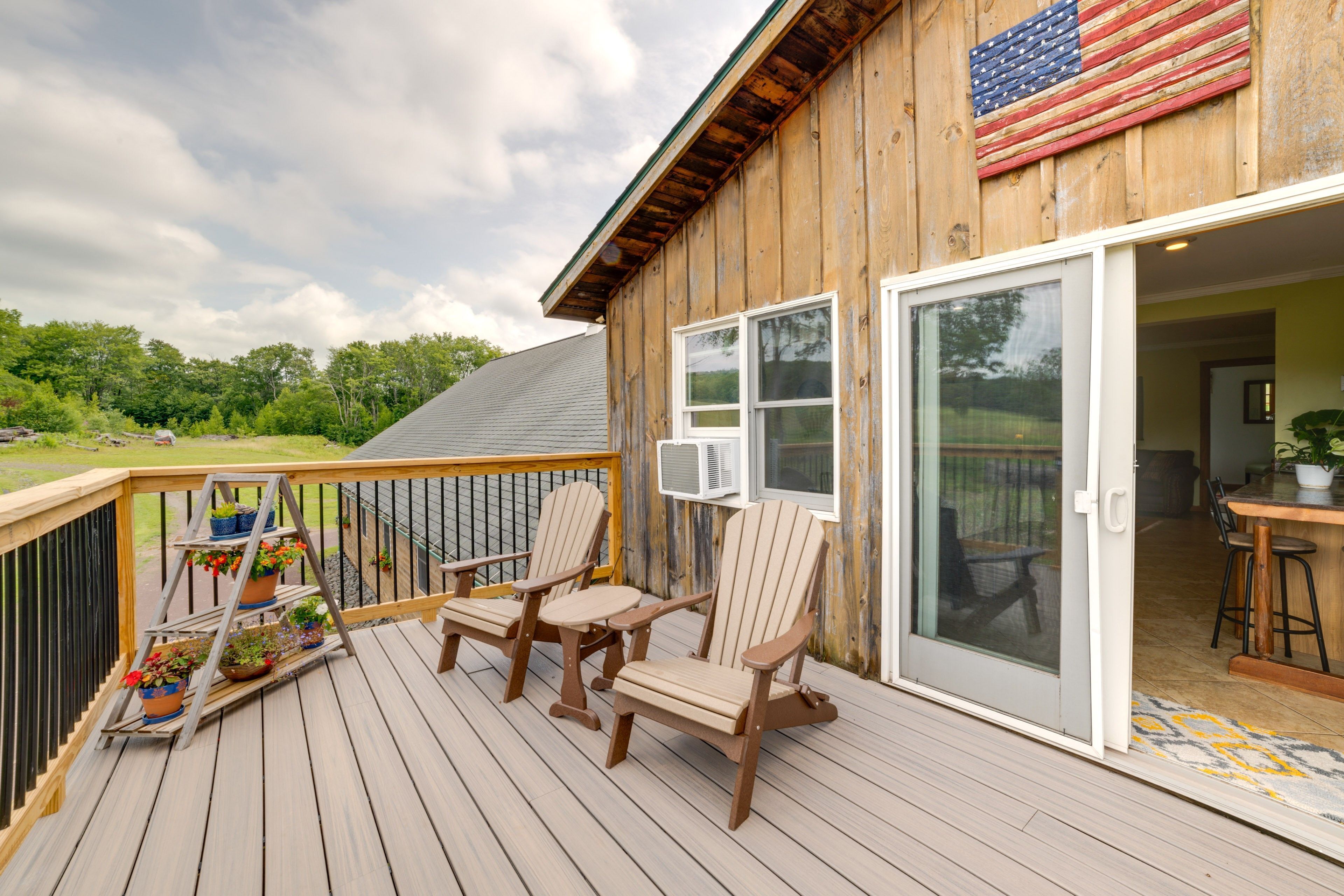 A wooden deck with Adirondack chairs, a small table, and a potted plant.