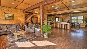 A spacious living area with a wooden ceiling, a sofa set, a coffee table, and a bar area with stools. - Lakeside Gem: Hot Tub & Game Room in Hancock (Hancock)