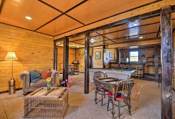 Une pièce chaleureuse avec une table de billard, des murs en bois et un coin salon confortable.