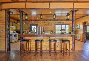 Une cuisine rustique aux murs en bois, avec un îlot central doté de tabourets et des lanternes suspendues.
