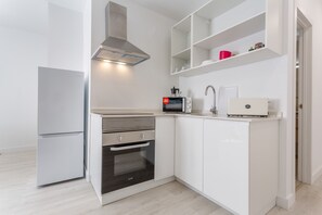 A compact kitchen with a built-in oven, microwave, and a coffee machine.