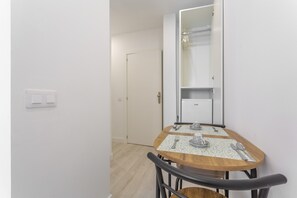 A small dining area with a table set for two, a mirror above the table, and a door leading to a closet.