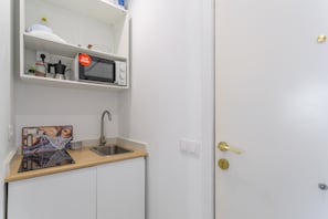 A compact kitchenette with a microwave, coffee maker, and a small sink.