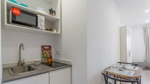 A kitchenette with a microwave, sink, and a dining area with a table and chairs.