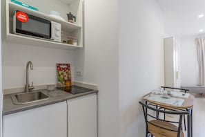 A kitchenette with a microwave, sink, and a dining area with a table and chairs.