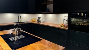 Cocina moderna con encimera de madera, hervidor, pileta y horno empotrado.
