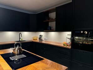 A modern kitchen with a wooden countertop, a kettle, a sink, and a built-in oven. - 180sqm Penthouse 2 Bedrooms incl. Terrace & Underground Parking (Rostock)
