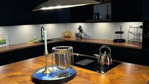 Una cocina moderna con encimera de madera, una tetera, una cafetera y una lámpara colgante.