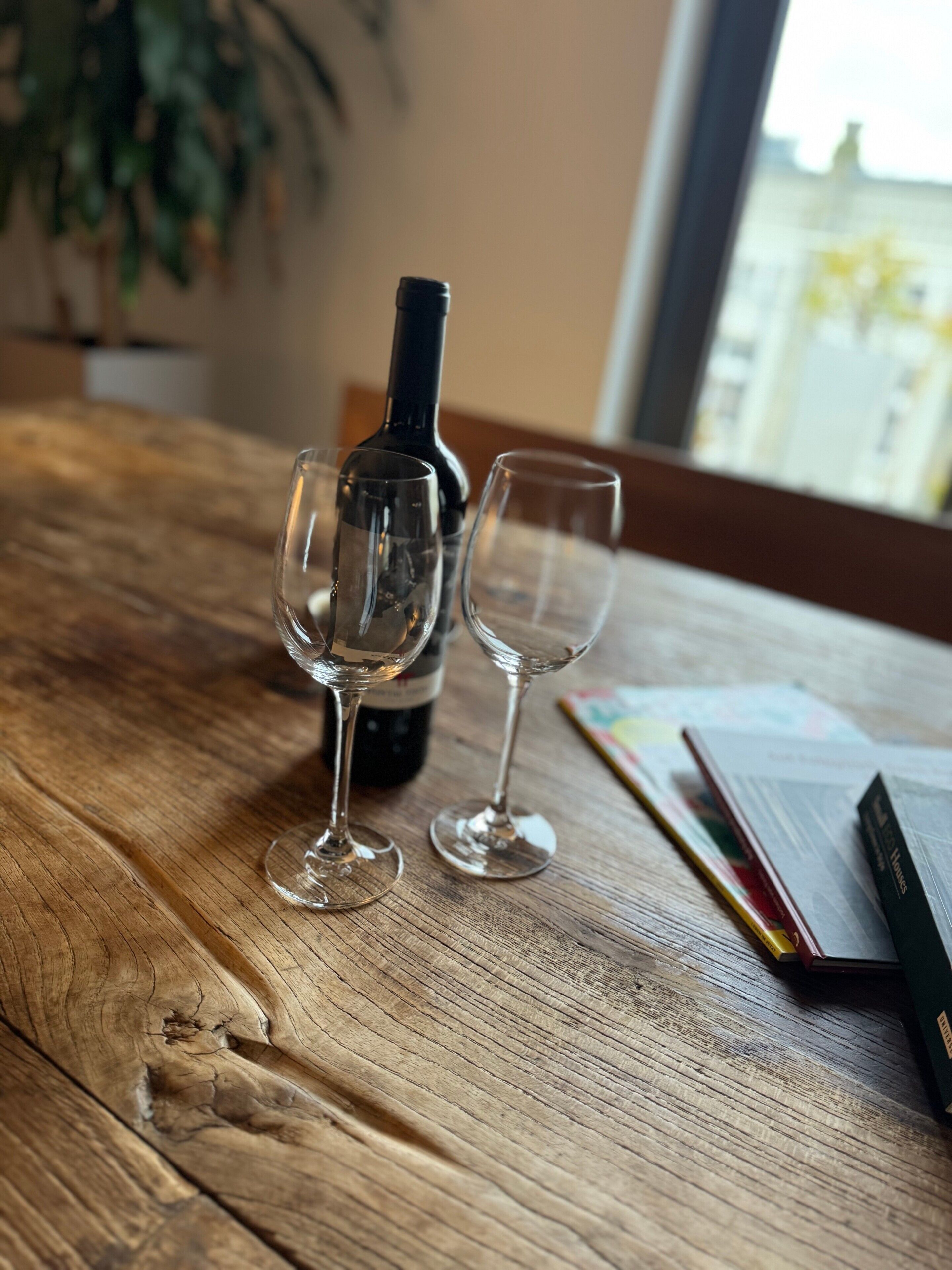 A wooden table with a wine bottle and two wine glasses.