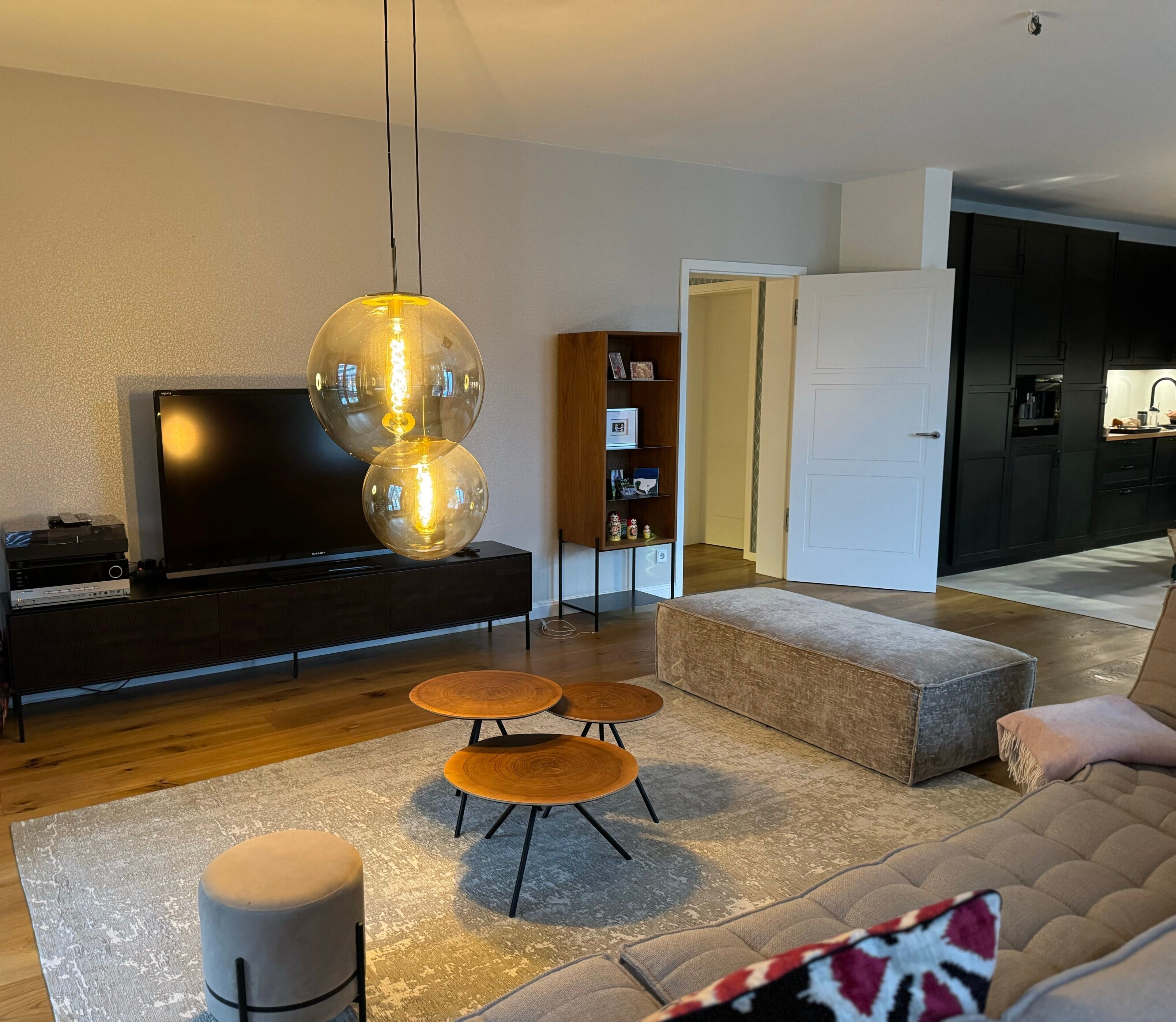 A modern living room with a sofa, ottoman, coffee table, and a TV.