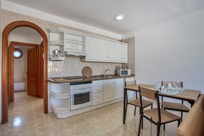 A kitchen with white cabinets, a microwave, and a dining area with wooden chairs and a table.