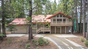 A two-story building with a red roof, a covered porch, and a garage.