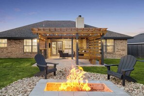 Une terrasse dotée d’un foyer extérieur, de sièges et d’une pergola.