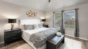 A bedroom with a bed, bedside tables, a bench, a ceiling fan, and a window with curtains. - Backyard Oasis: Smart Home w/ Alexa & Fire Pit (Killeen)
