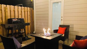 Un patio al aire libre con una parrilla de carbón, una chimenea y mobiliario de mimbre.