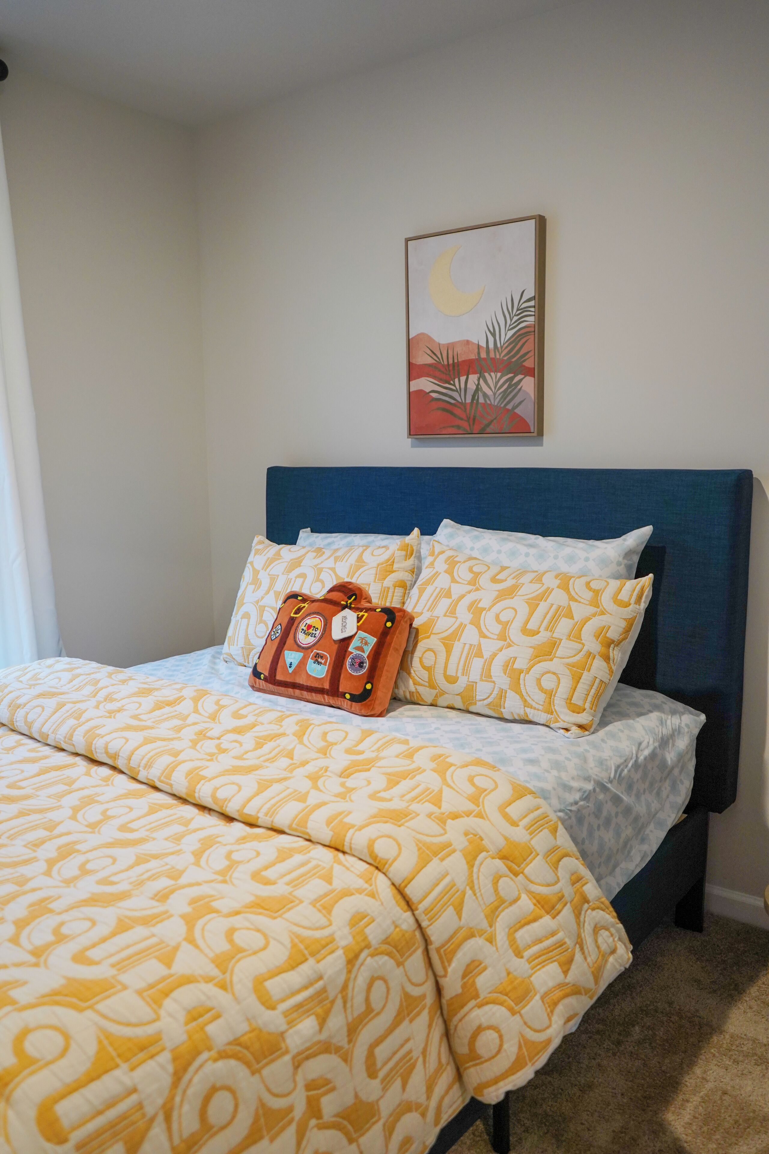 Un lit bien fait, avec une literie à motifs et un coussin décoratif.