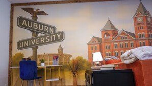 Una habitación con un mural de la Universidad Auburn, un escritorio con silla, una lámpara y una cama.