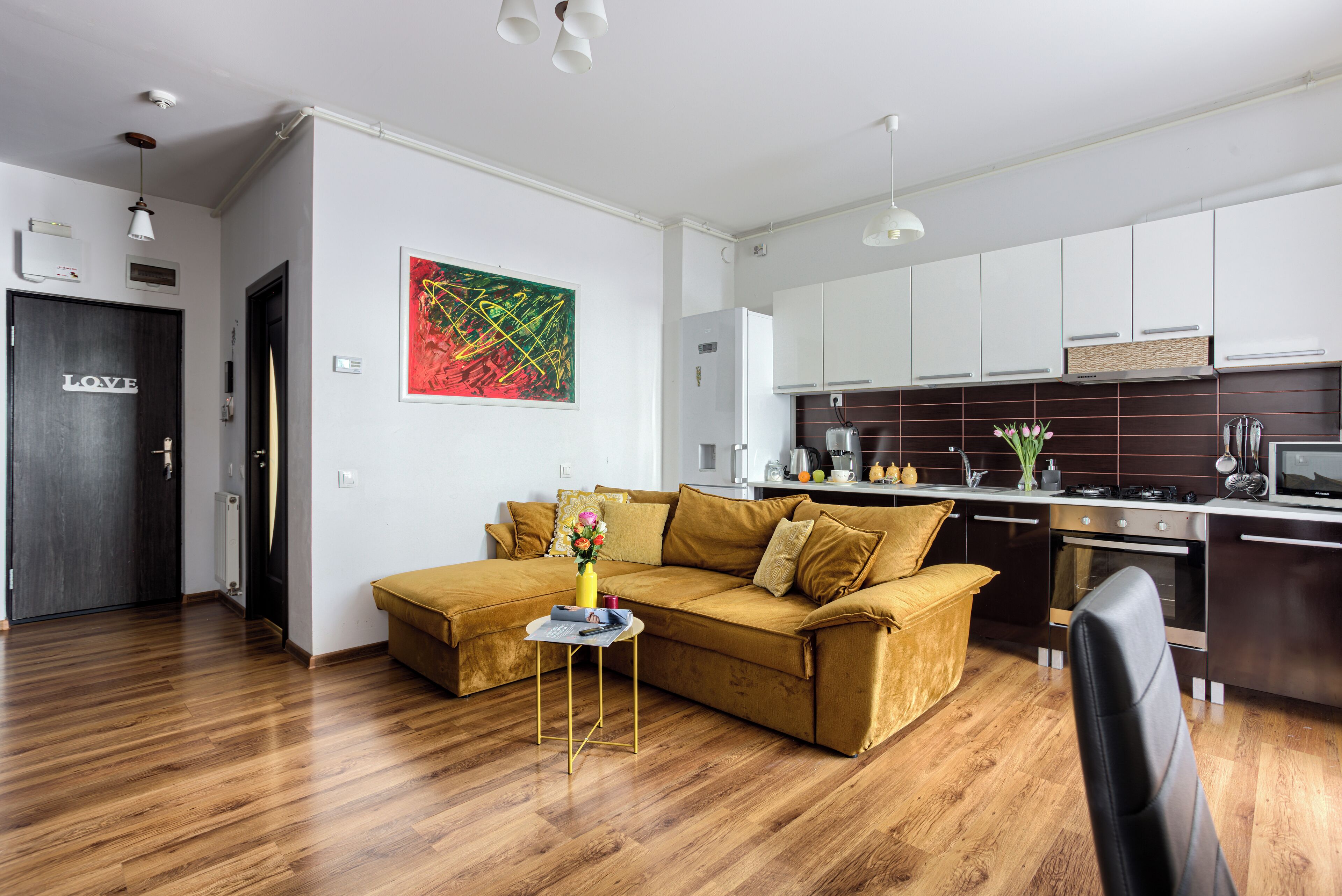 Ein modernes Wohnzimmer mit einem braunen Sofa, einem kleinen Beistelltisch und einem Gemälde an der Wand.